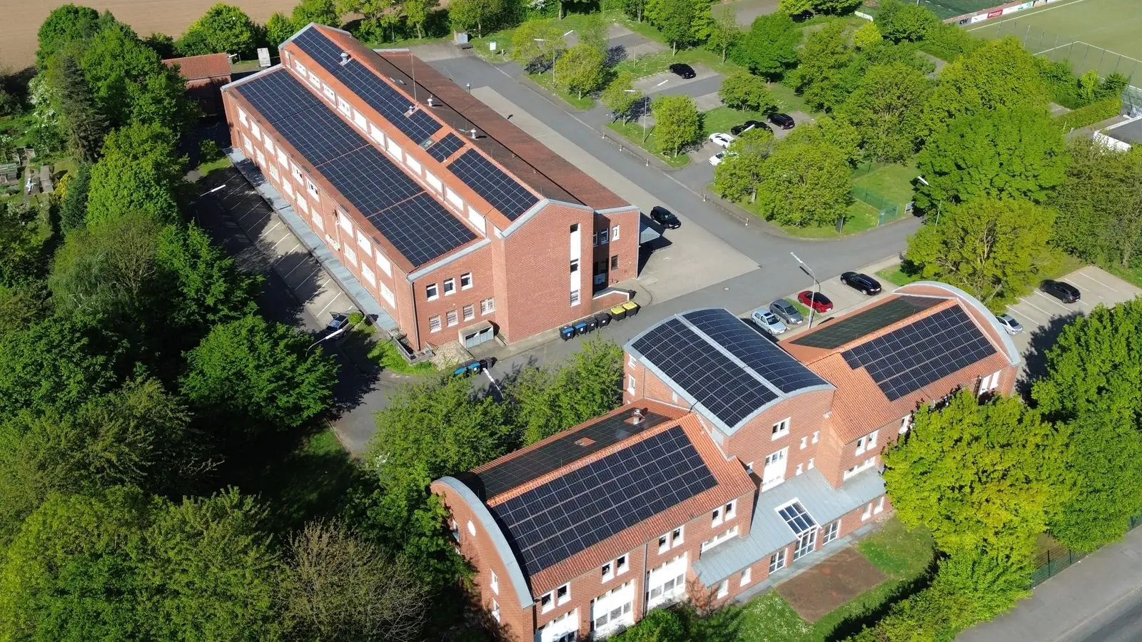 Luftaufnahme mehrerer Gewerbegebäude, deren Dächer vollflächig mit Photovoltaikmodulen belegt sind